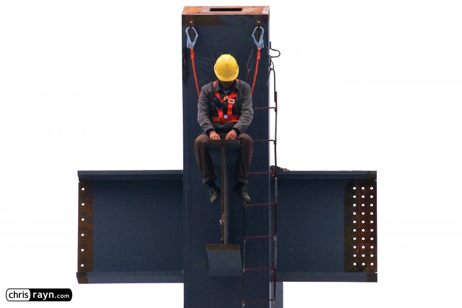 Construction worker chained high up to massive steel column