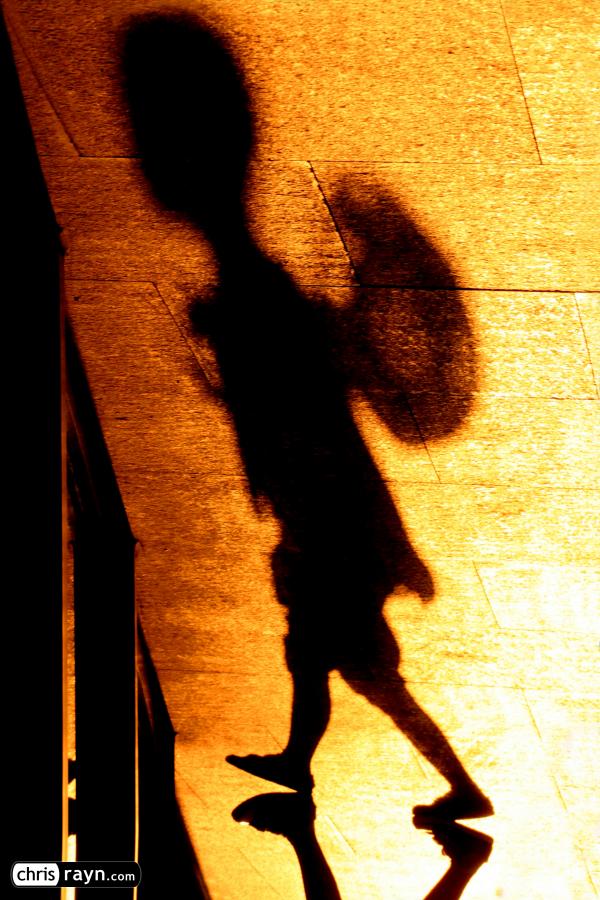 In shadows, a boy with hat is wandering 