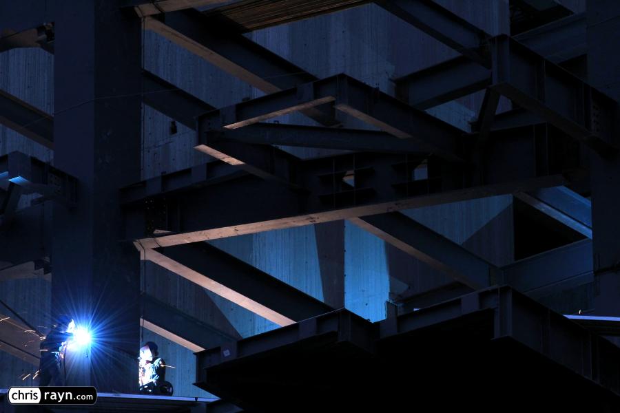 Welders light up a construction site at night