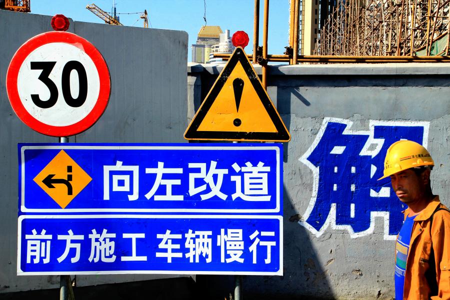 A Worker Passes By a Construction Sign At Shanghai's Old Tow
