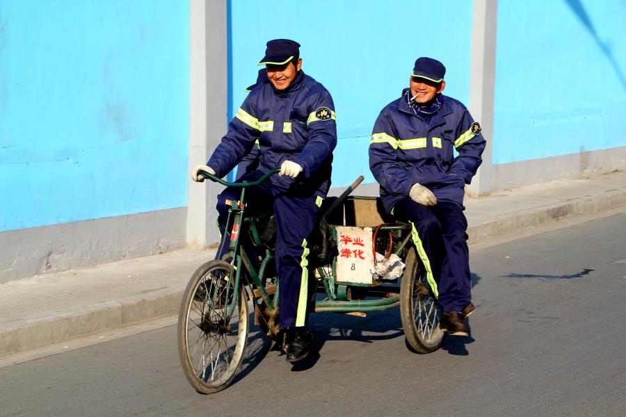 Workers on a Tricycle Pass By Laoximen Demolition Wall