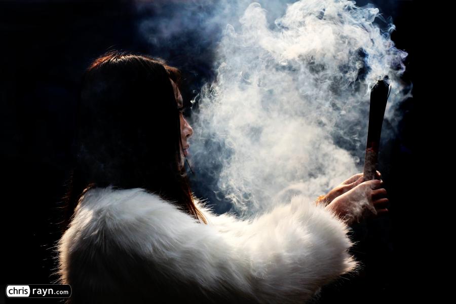 A young woman clad in white fur, and white incense smoke