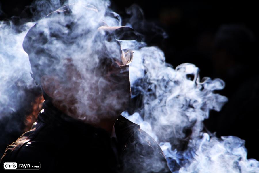 Smoke billows around a spectacled man in the Chinese temple