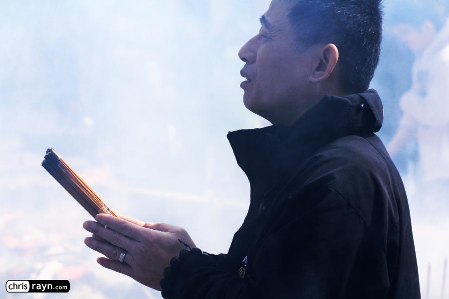 A praying man in front of a wall of smoke in the temple