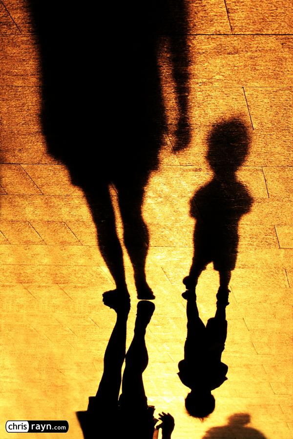 Shadows of a toddler, walking with his mother