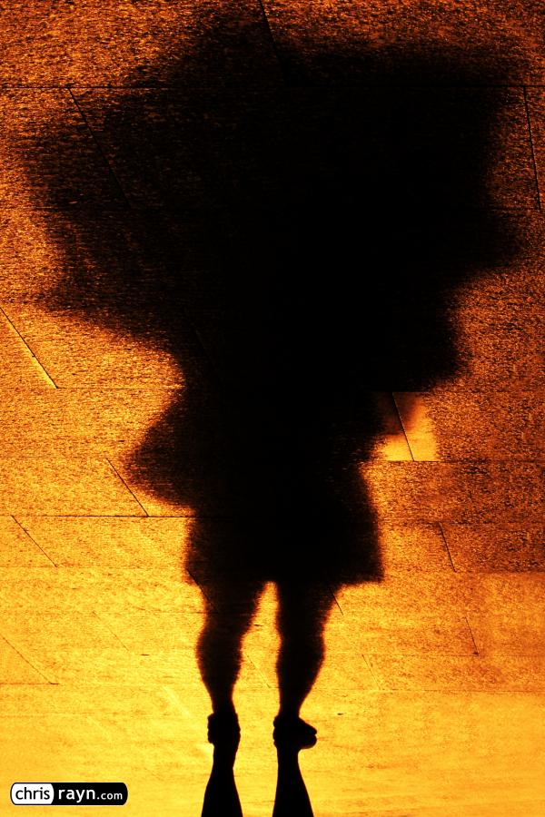 Woman taking refuge in the shadows of her umbrella