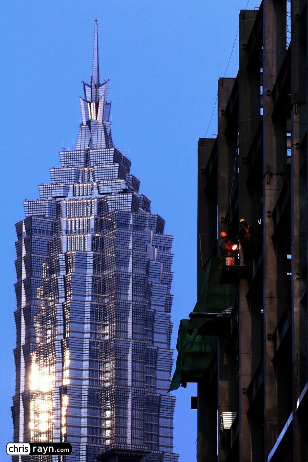 Welders constructing new buildings in front of Jinmao Tower