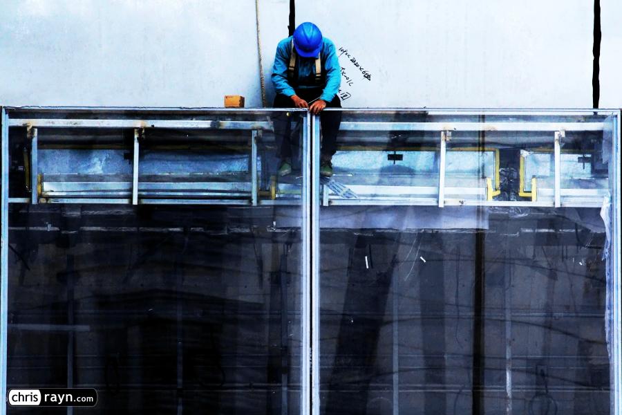 Construction worker on top of a giant glass door